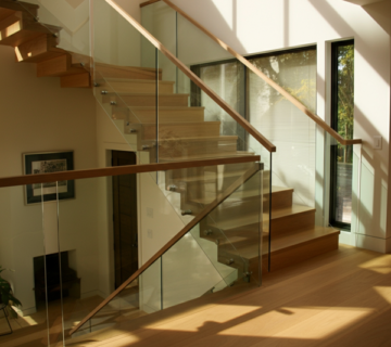 Modern staircase featuring Invisirail Glass Railing with wooden handrails and steps.